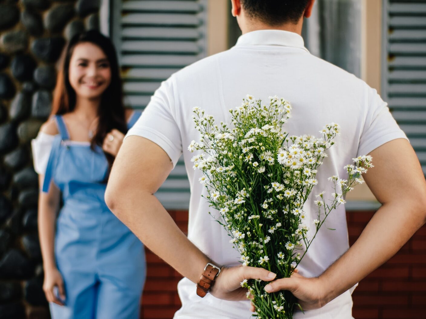 Man Holding Baby's-breath Flower in Front of Woman Standing Near Marble Wall