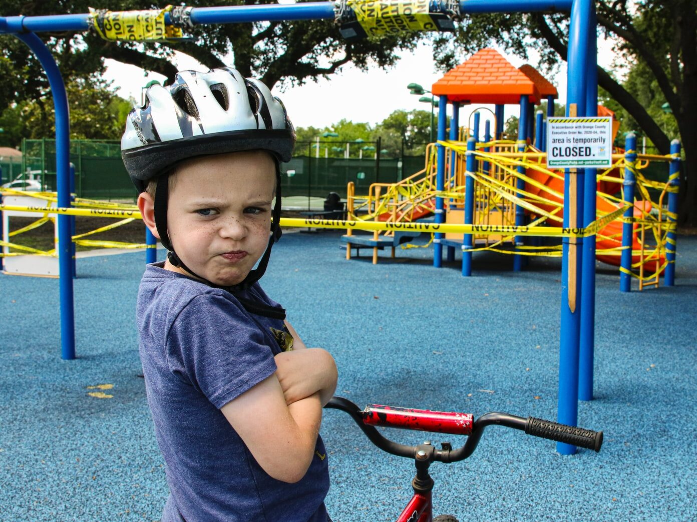 boy in blue denim vest and helmet riding red bicycle