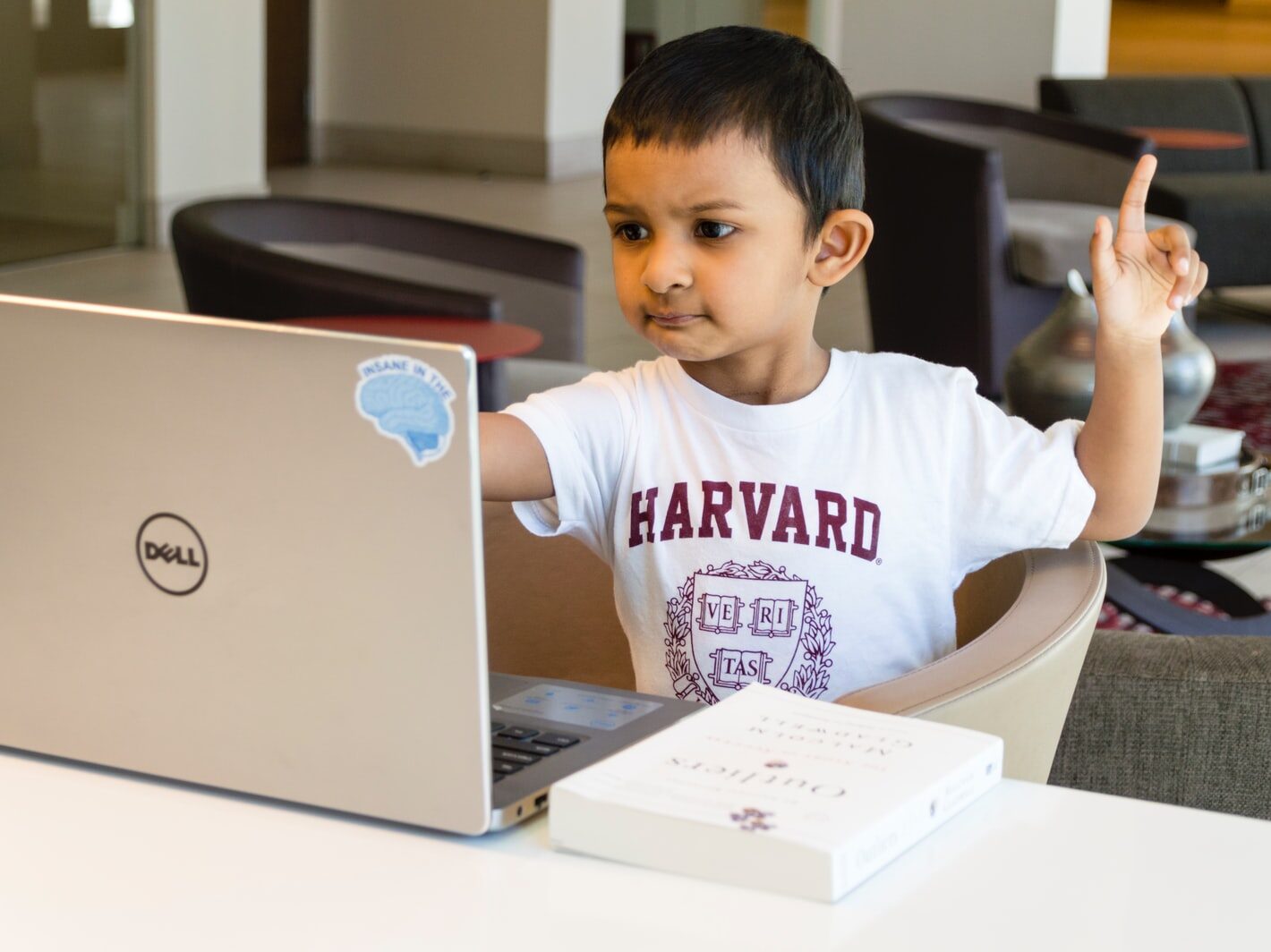 boy in white and red crew neck t-shirt sitting on chair