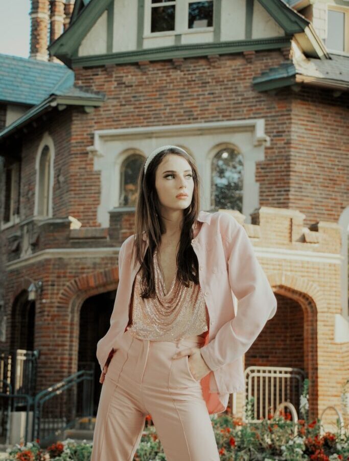 woman in pink long sleeve dress standing near brown brick building during daytime