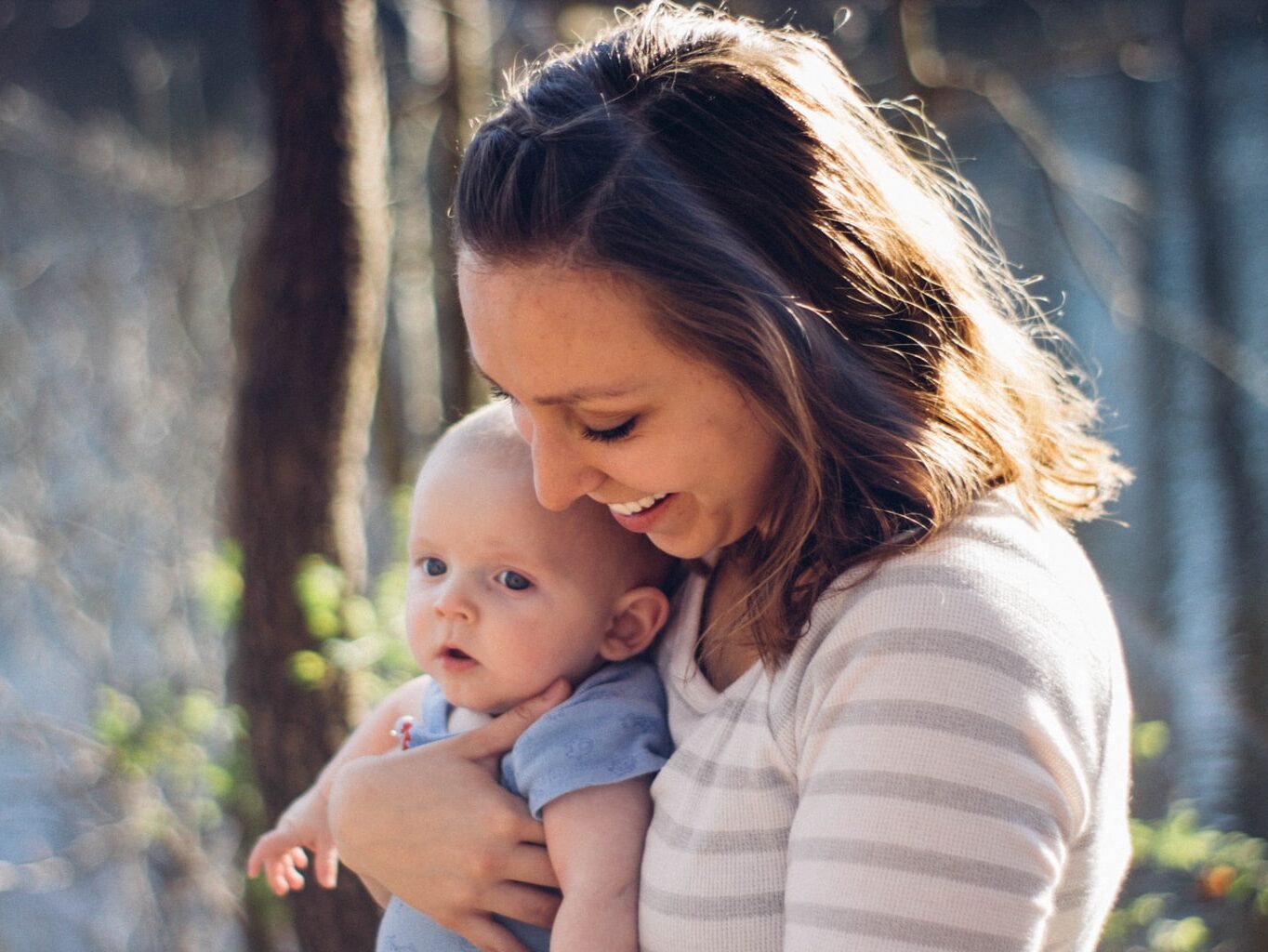 woman carrying baby near trees