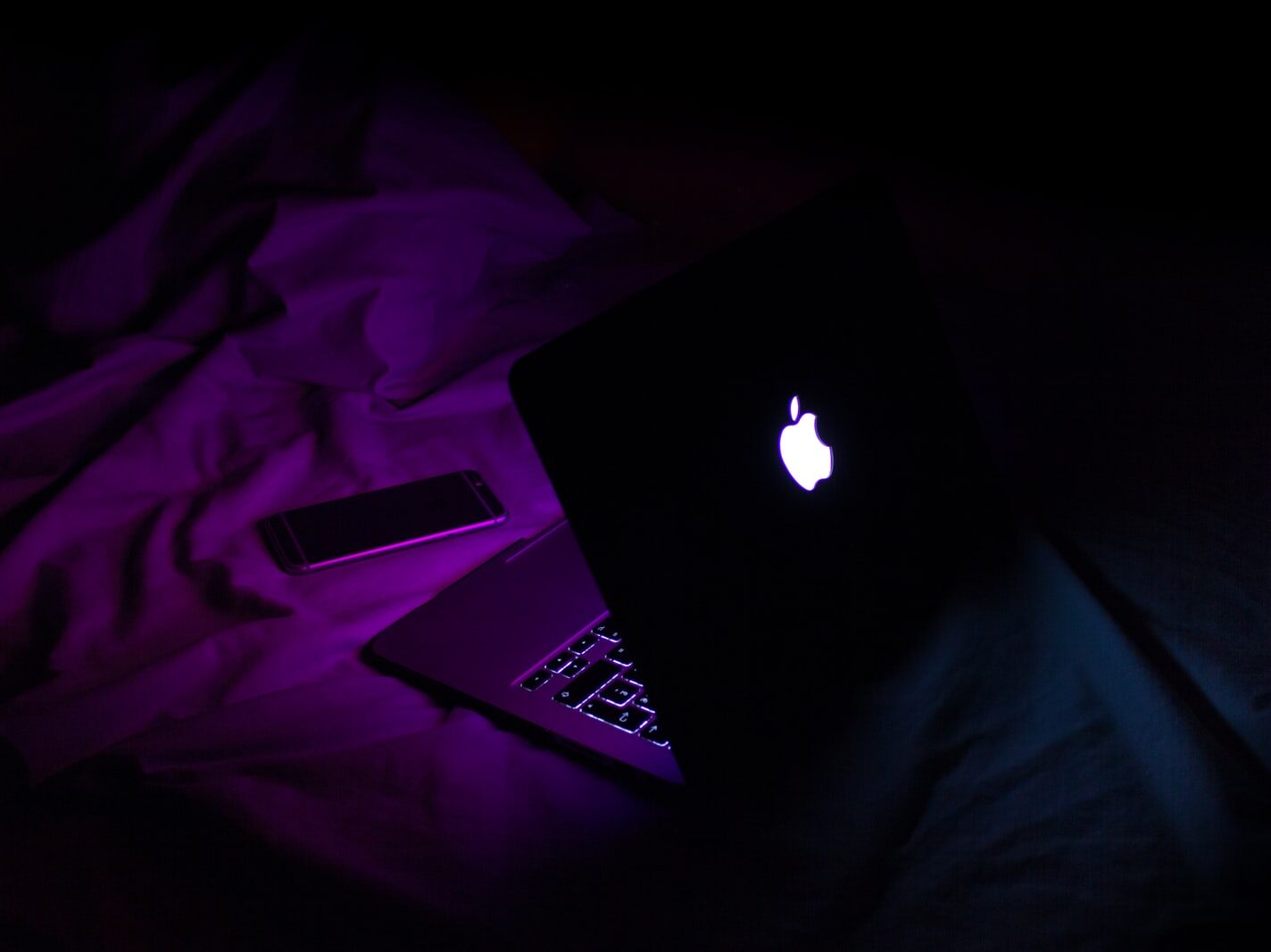 silver MacBook beside smartphone