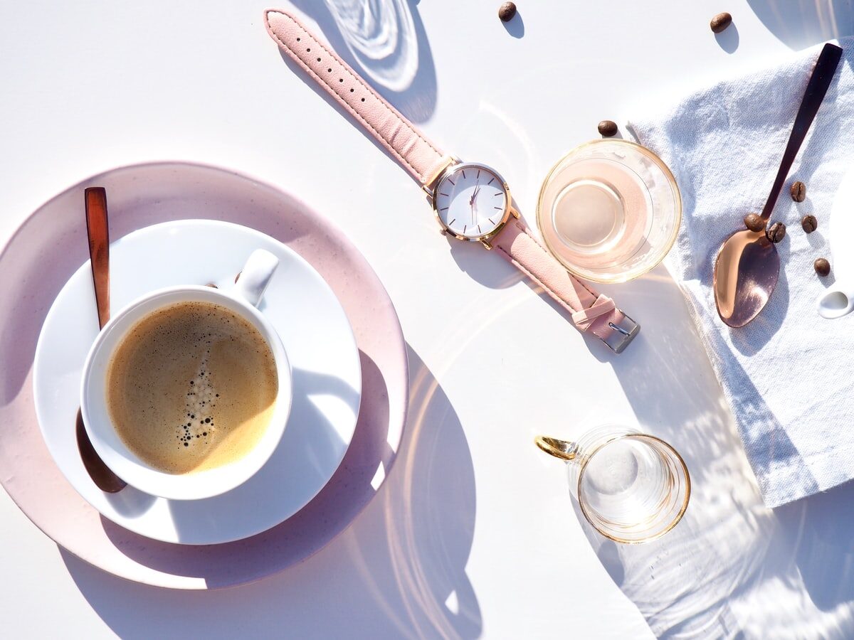 round gold-colored analog watch displaying 12:41 near cup of coffee