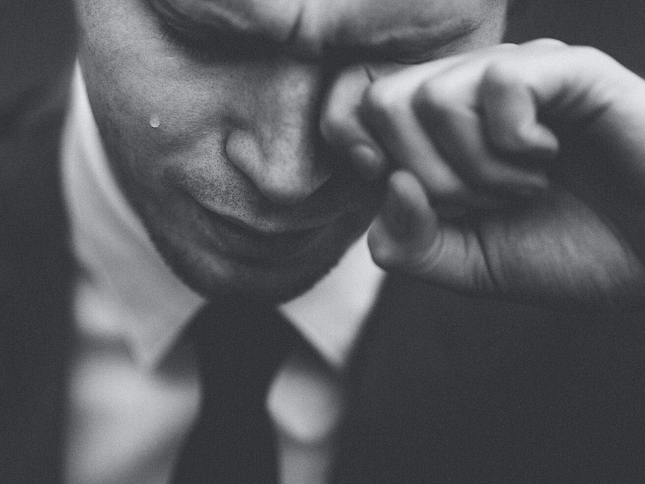 man wiping his tears