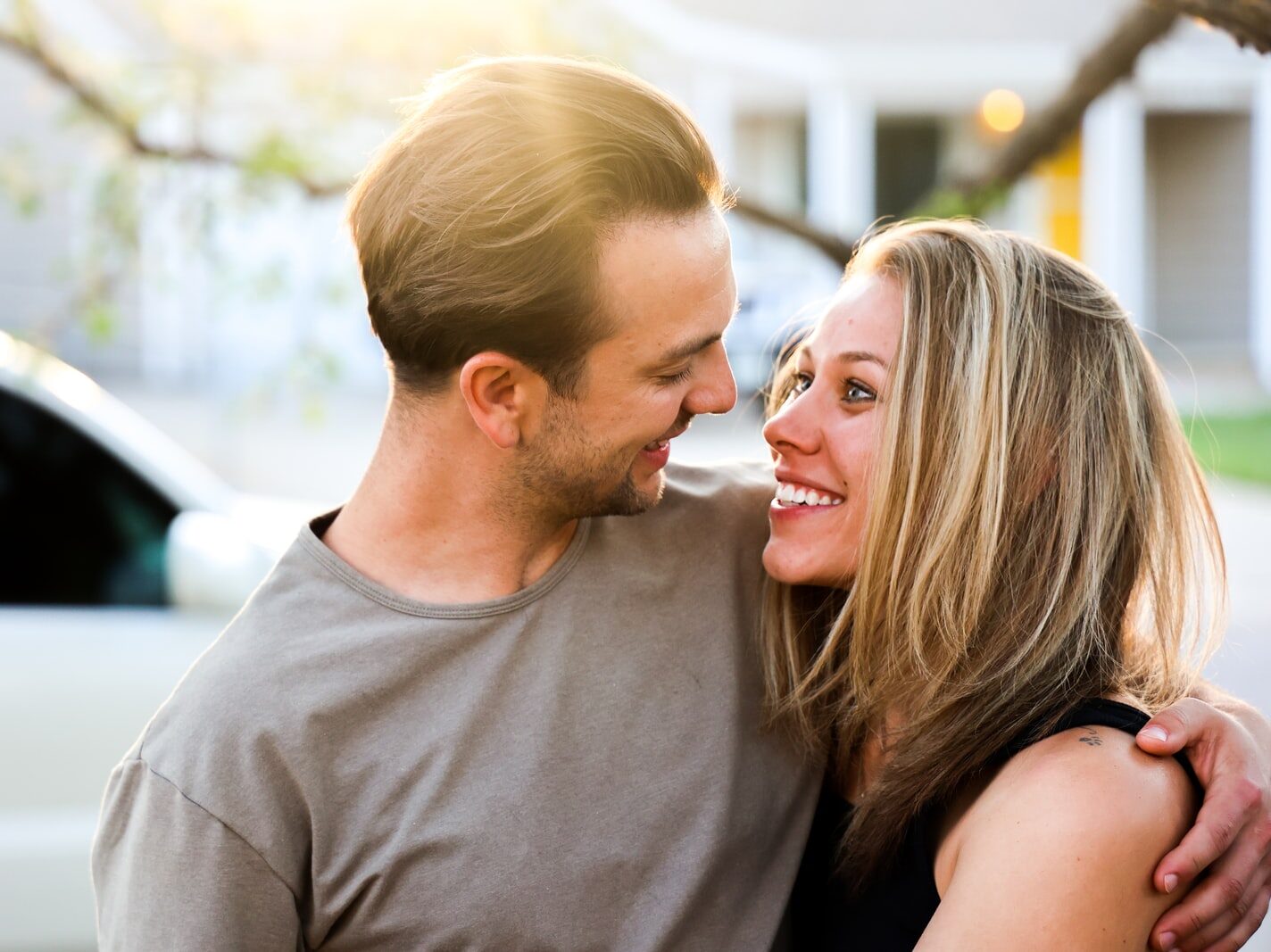 man in gray crew neck shirt kissing woman in black tank top