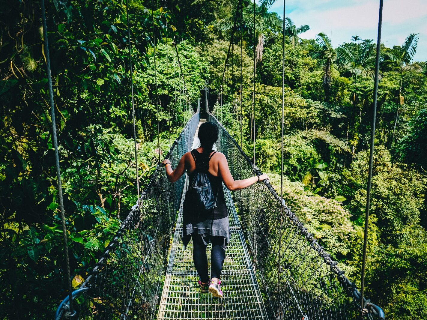 woman in black shirt and black pants standing on hanging bridge