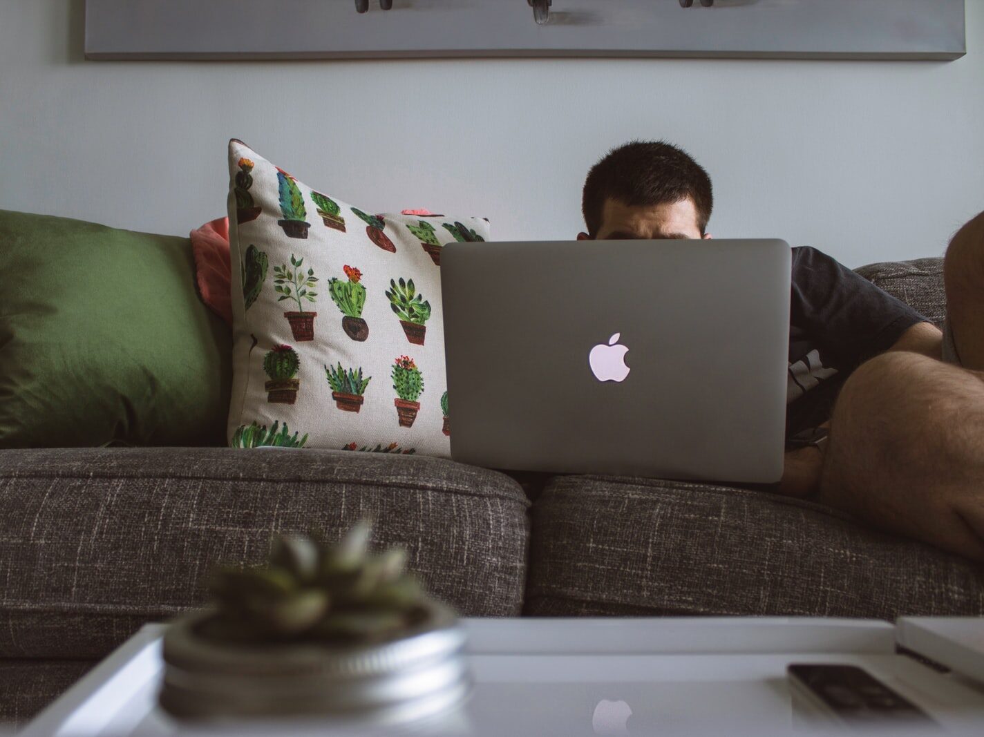 man using MacBook sat on sofa