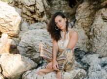 A Woman Wearing a Crochet Top and Floral Pants Sitting on a Rock