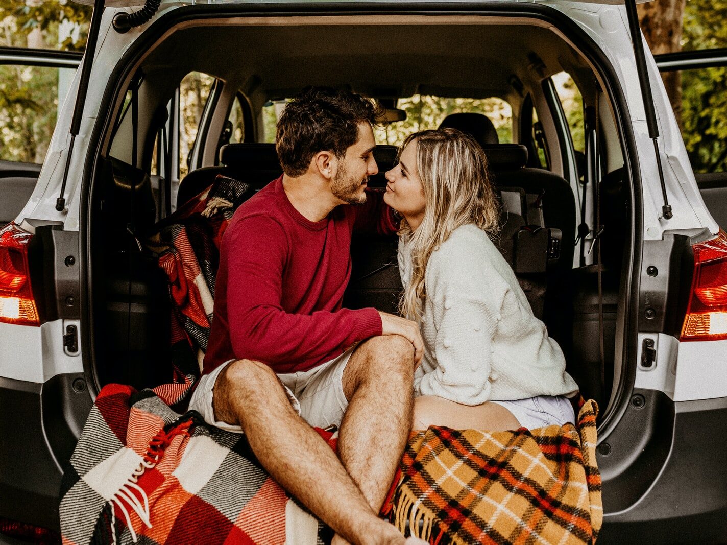 man and woman sitting on car's trunk