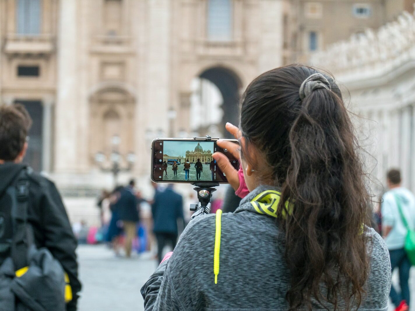 woman in gray hoodie holding black smartphone
