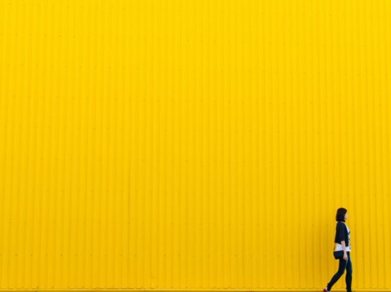 woman wearing black top standing near yellow wall