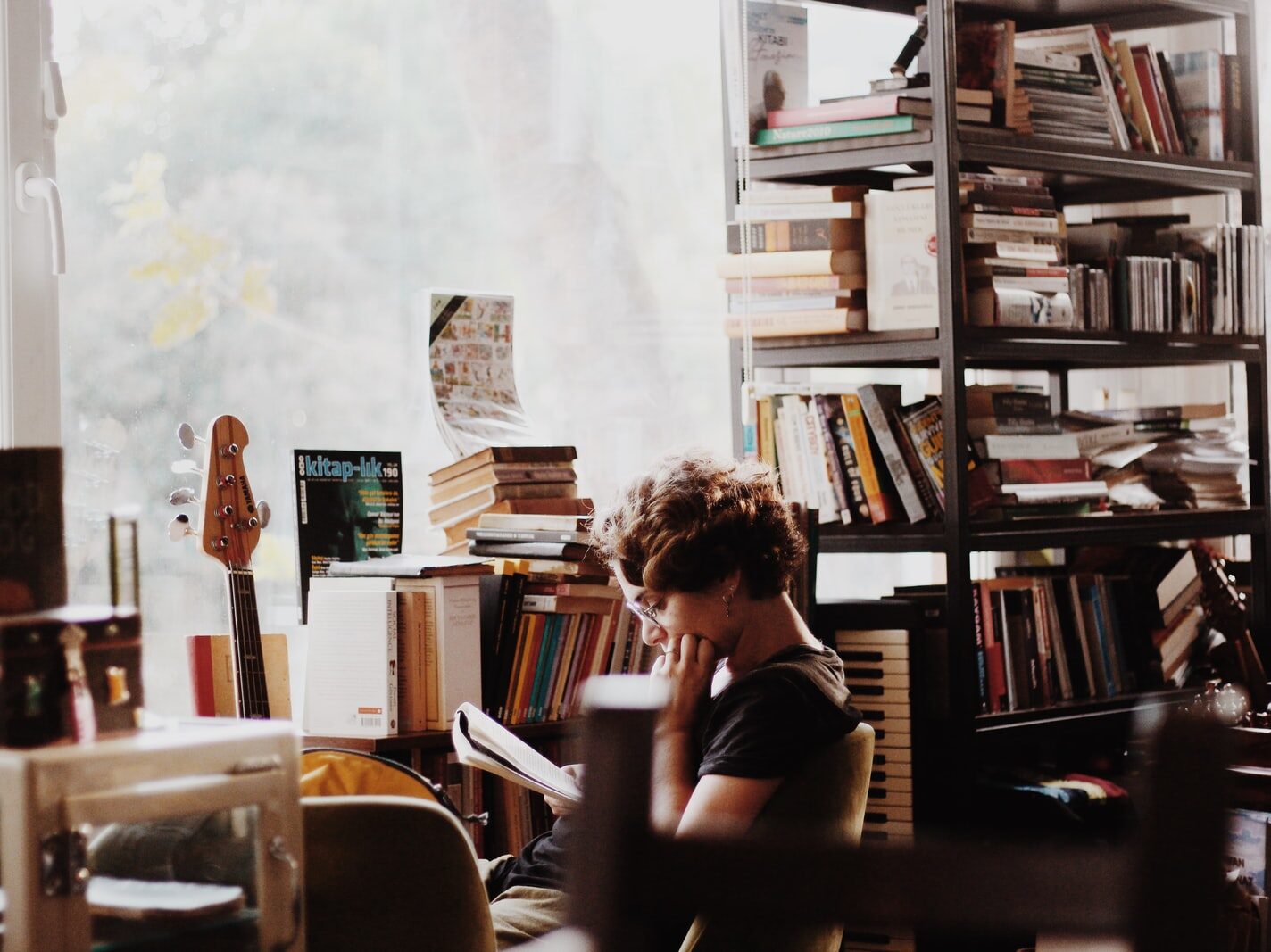 woman reading book sitting beside electronic keyboard