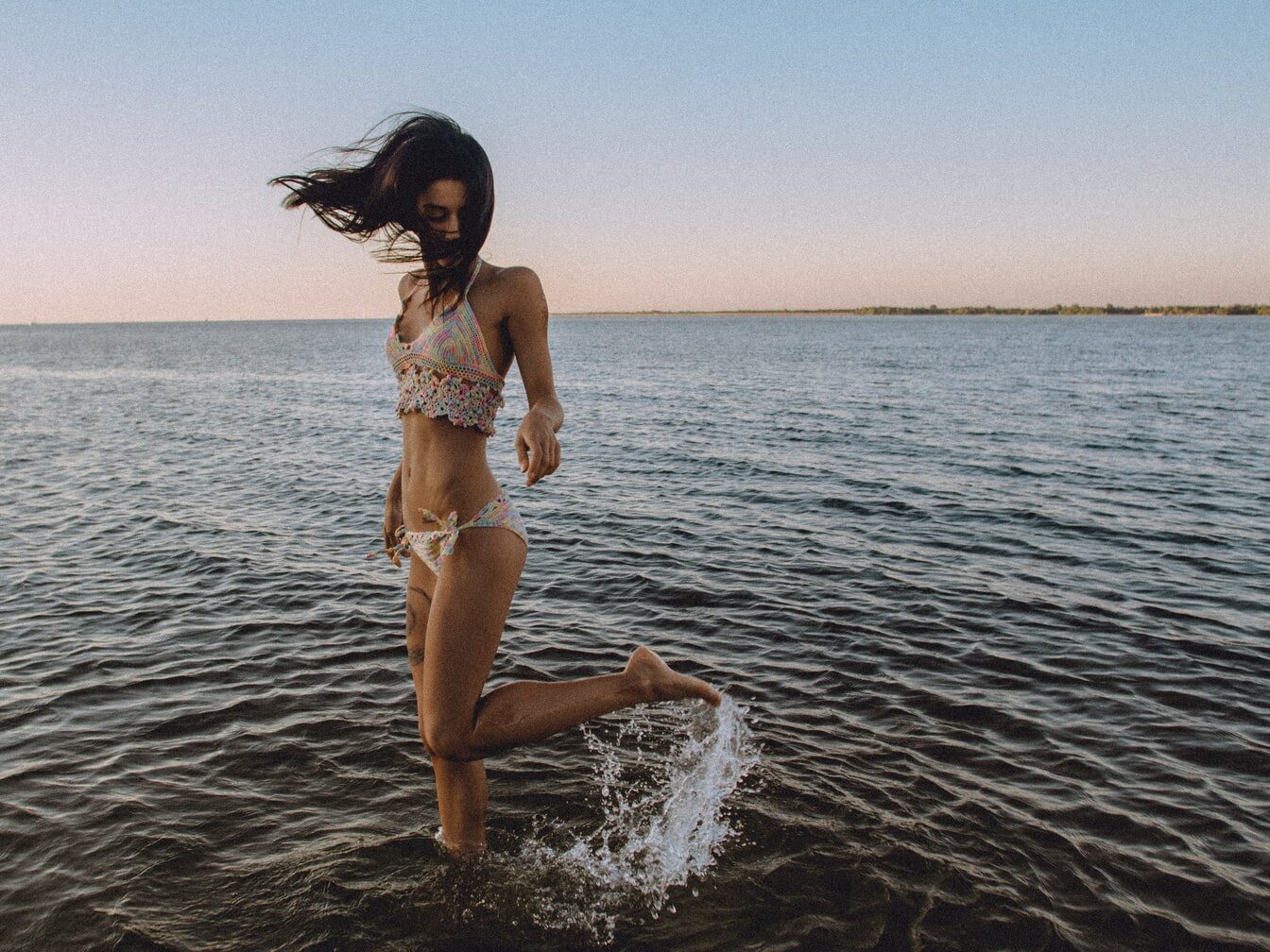 - ČasProŽeny.cz A girl in a bikini flicks her leg up behind her in the water at a beach
