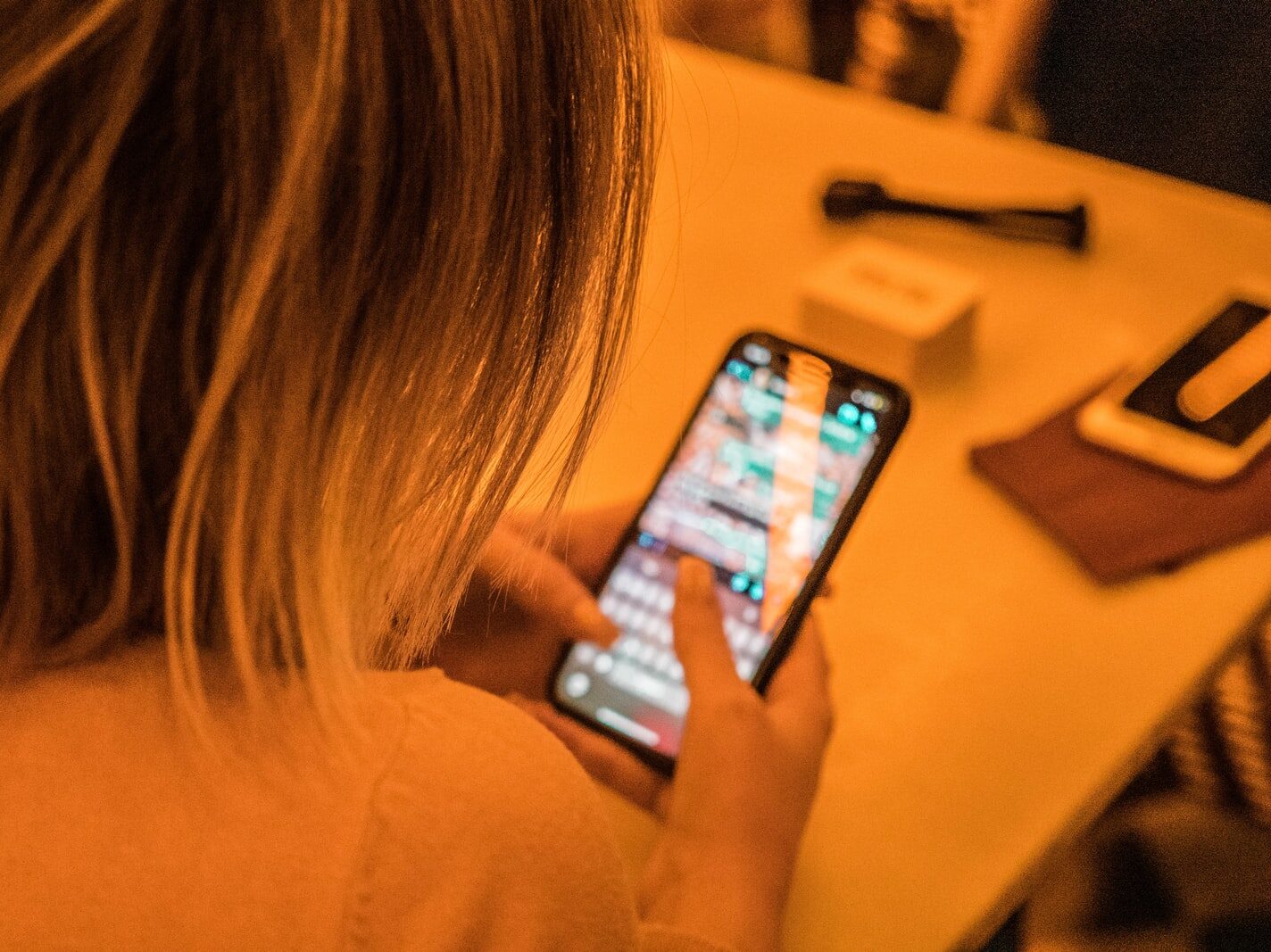 woman in white shirt holding black iphone 4