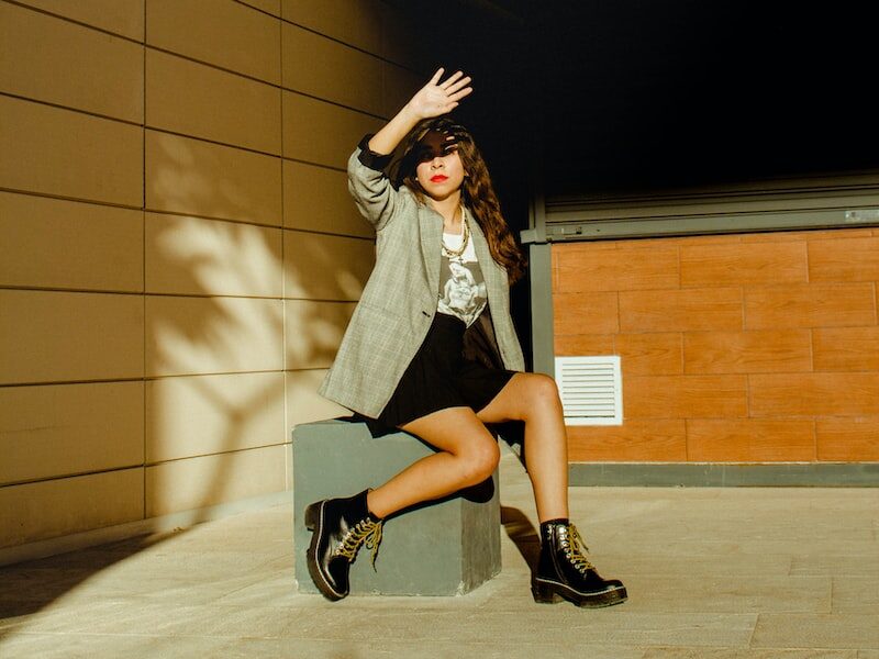 woman in white long sleeve shirt and black skirt standing beside brown wall