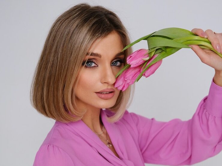 Woman in Pink Shirt Touching Her Face with Pink Flowers