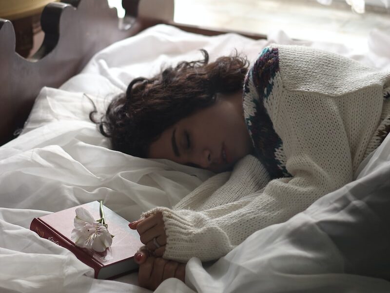 woman sleeping on bed beside book