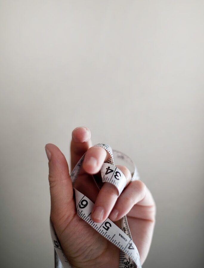 person's left hand wrapped by tape measure