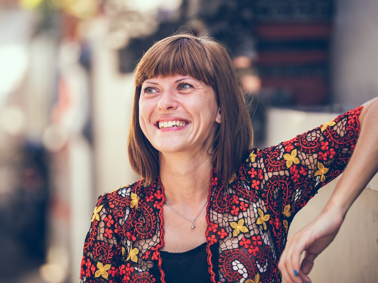 woman in floral-themed cardigan leaning on fence in bokeh photography