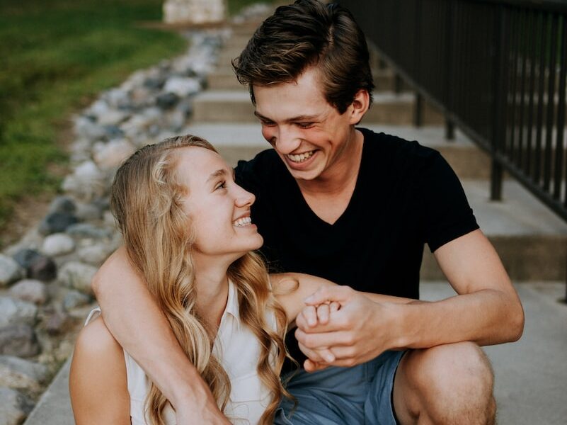 man holding the hand of a woman while siting on concrete staircase