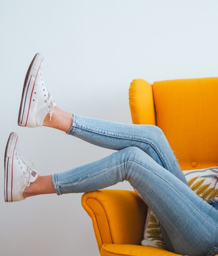 woman in blue denim jeans and white converse all star high top sneakers sitting on orange