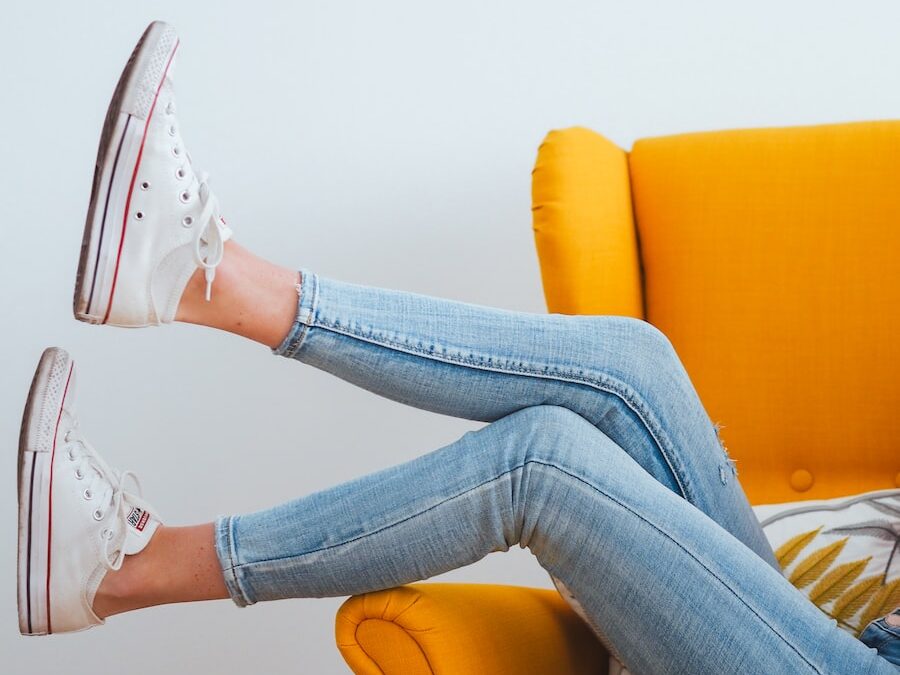 woman in blue denim jeans and white converse all star high top sneakers sitting on orange