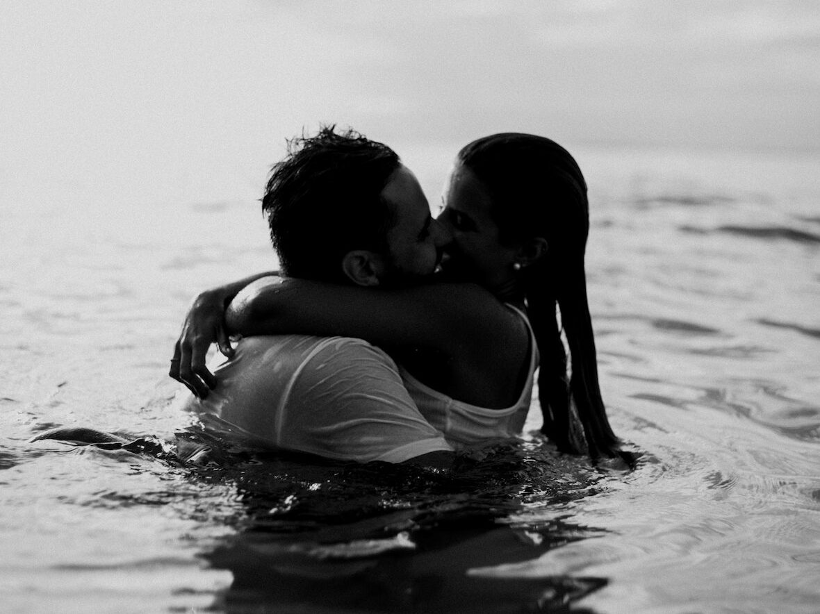 Man and Woman Kissing Together on Body of Water