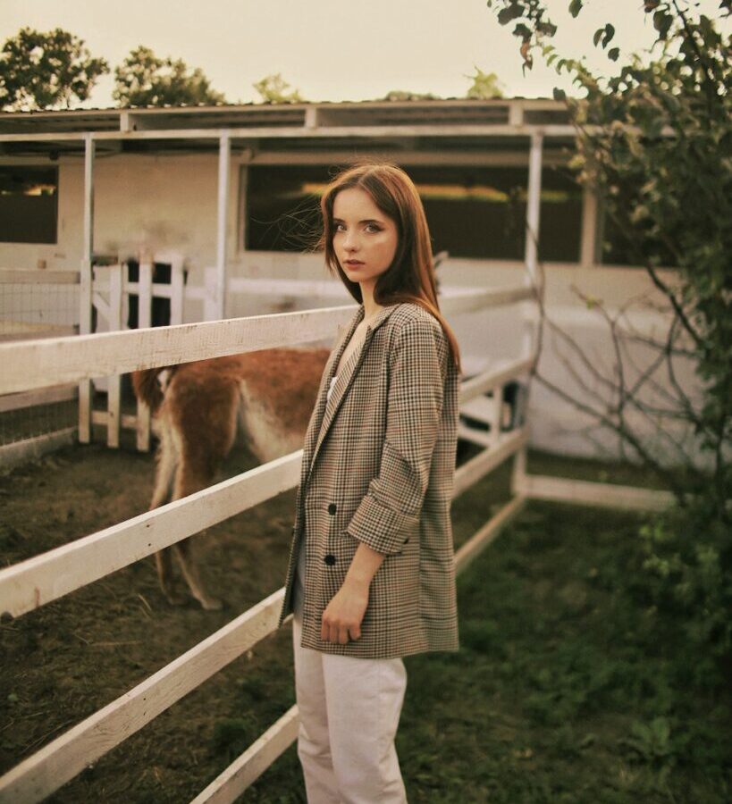 Woman in White and Black Polka Dot Long Sleeve Shirt and White Pants Standing on Green