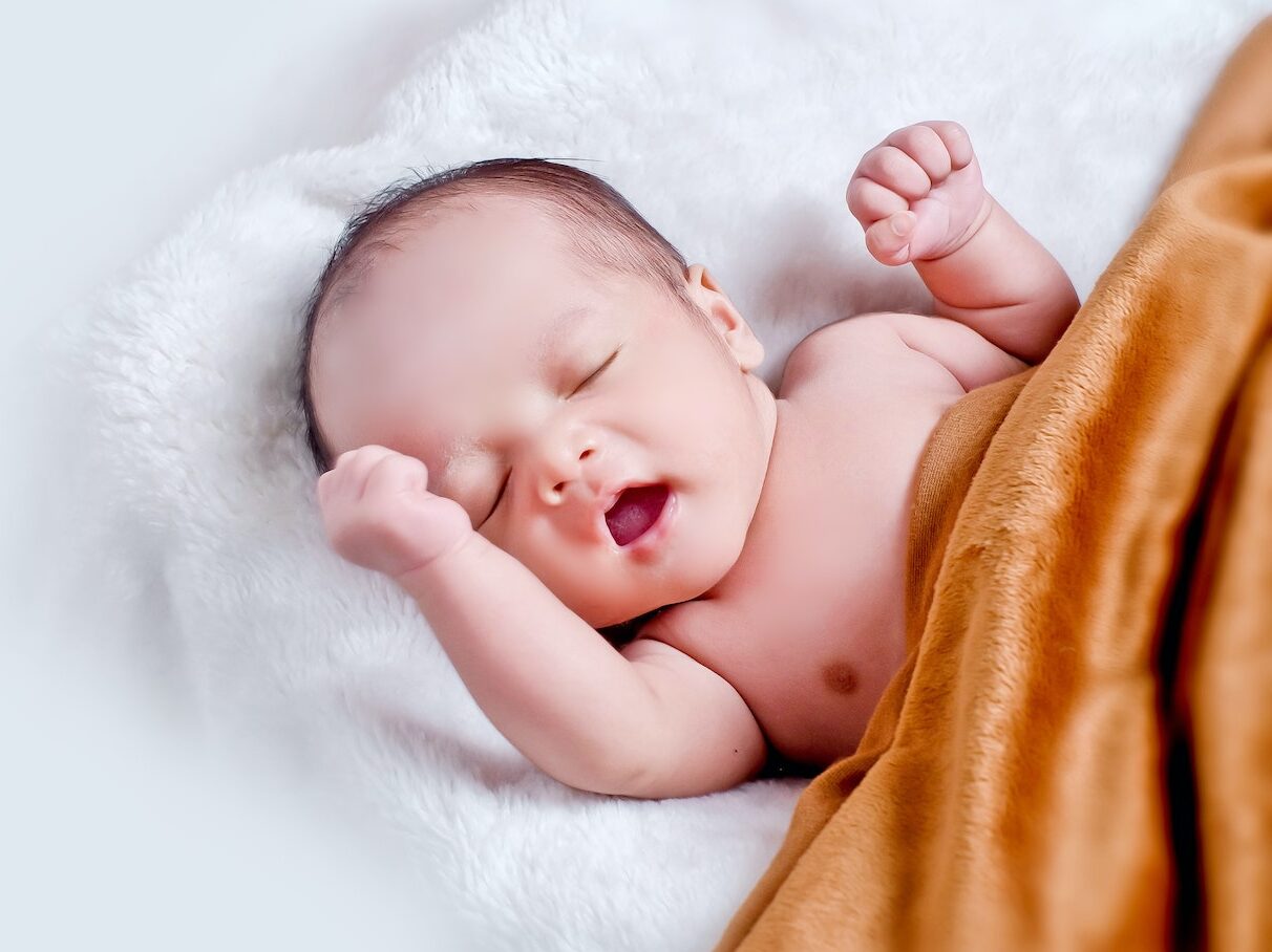 Baby Lying On White Fur With Brown Blanket