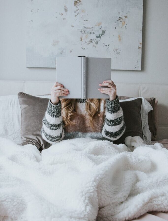 woman sitting on bed while holding book