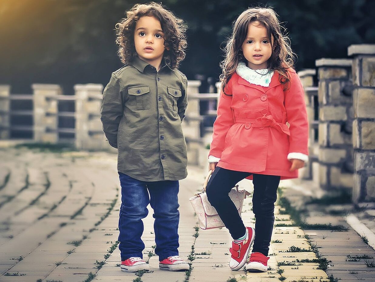 Two Children Standing Near Concrete Fence