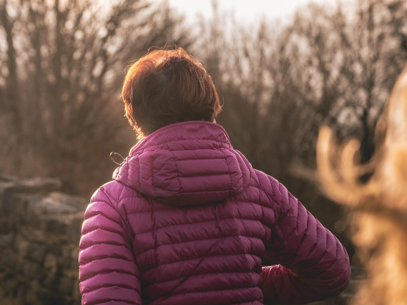 person wearing purple jacket standing near black wall