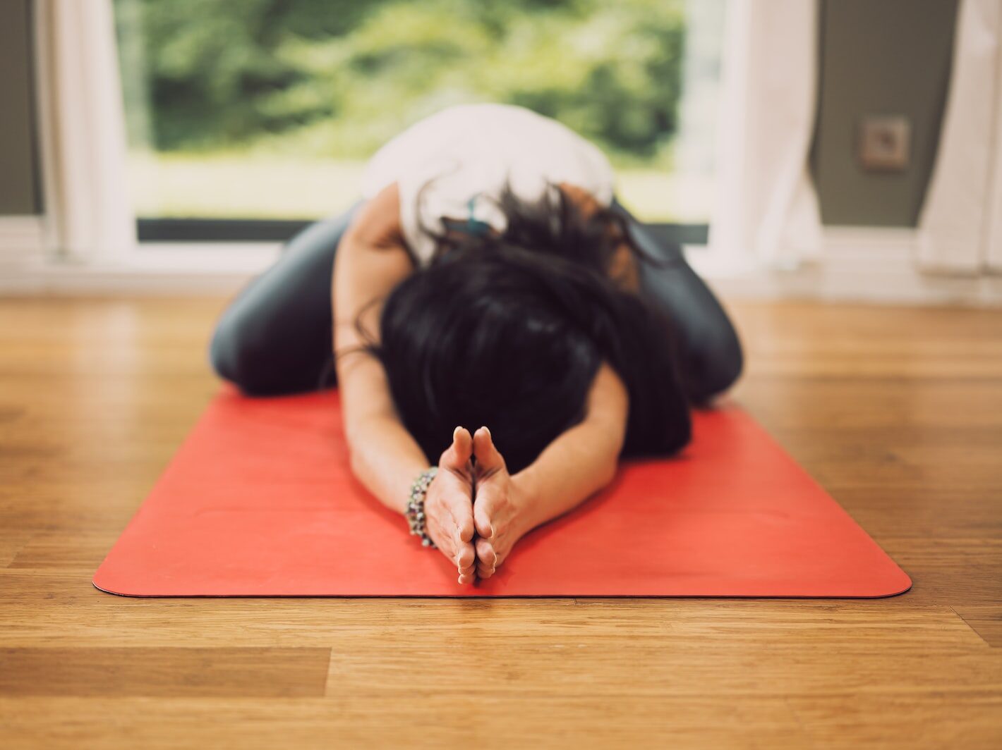 woman in white shirt lying on red mat on brown wooden table