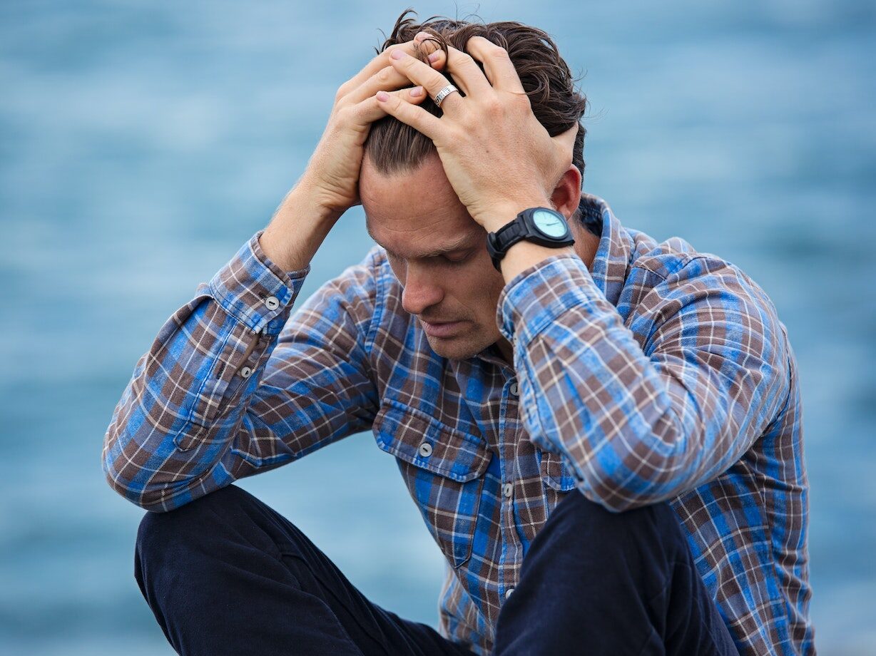 Man in Blue and Brown Plaid Dress Shirt Touching His Hair