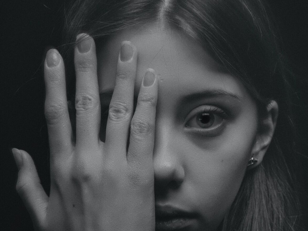 woman covering half of her face grayscale photography