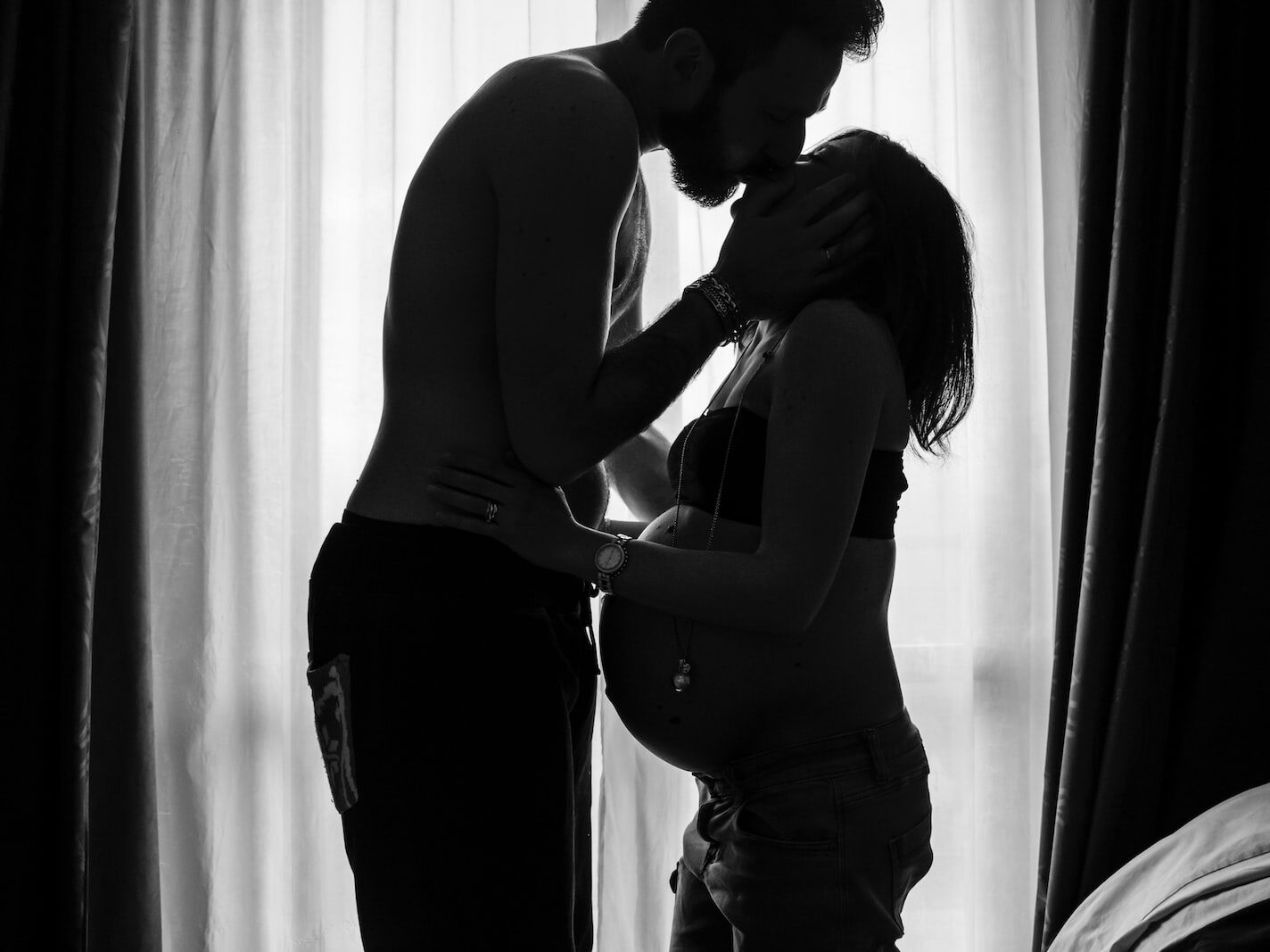 man standing near window kissing woman