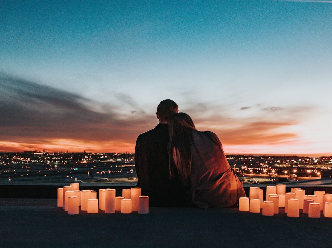 couple sitting on the field facing the city