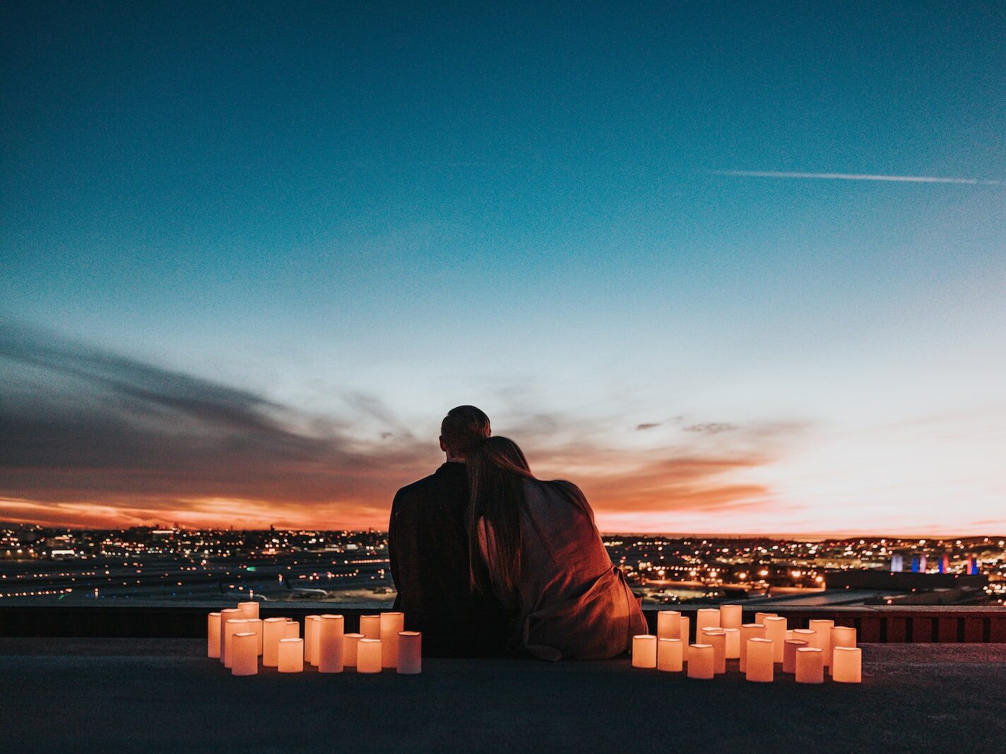 couple sitting on the field facing the city