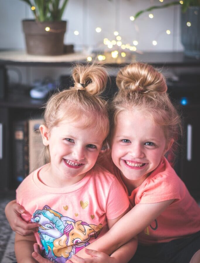 girl in pink crew neck t-shirt smiling beside girl in pink t-shirt