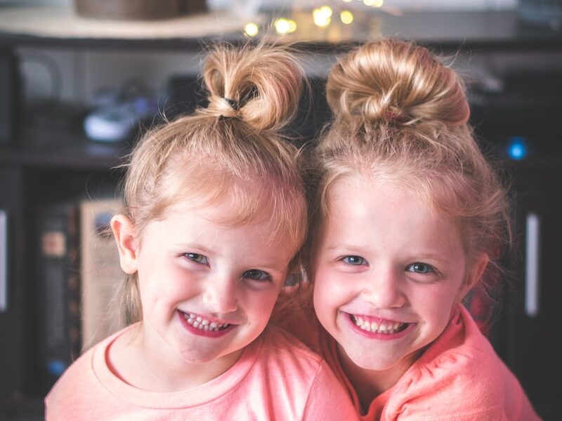 girl in pink crew neck t-shirt smiling beside girl in pink t-shirt