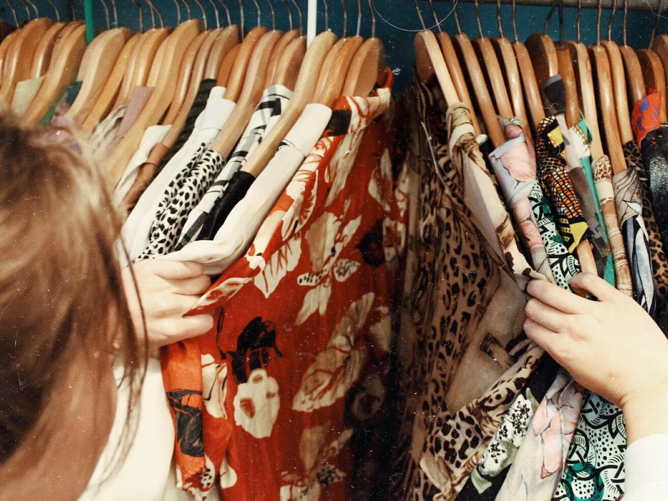 person holding assorted clothes in wooden hanger