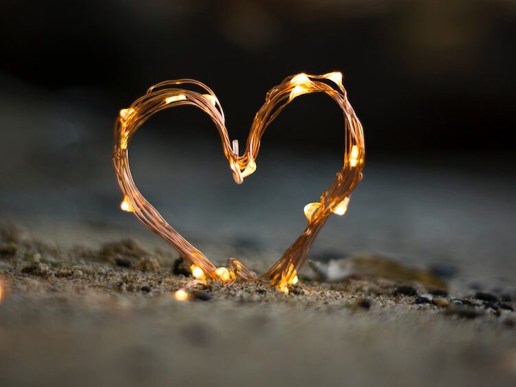 close-up photography of heart shaped fairy lite on brown sand
