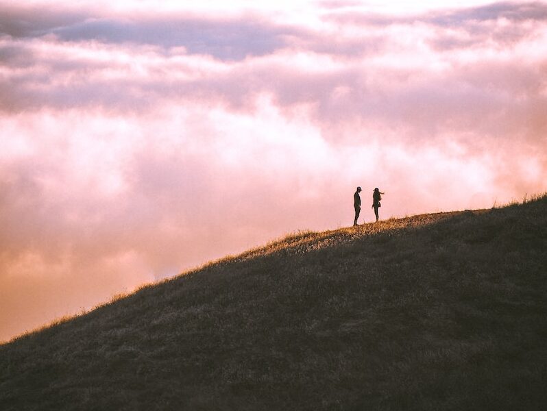 couple standing on grass field mountain