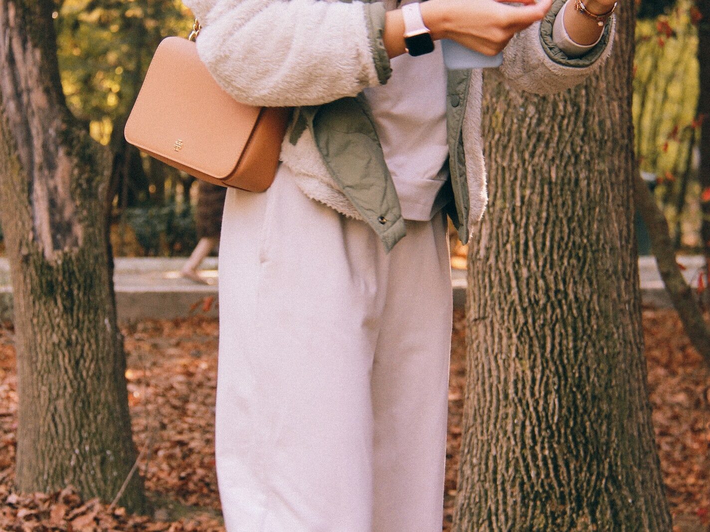 person in white dress shirt and brown pants holding brown leather bag