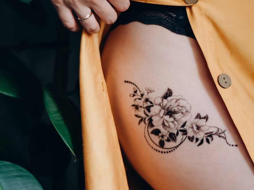 woman in orange button up shirt with black floral tattoo on her back