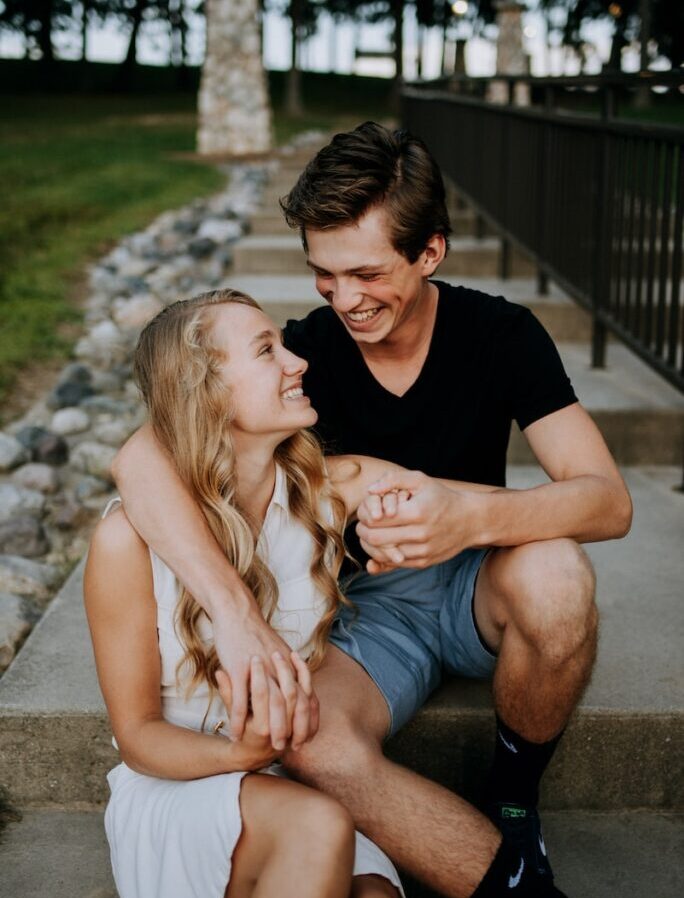 man holding the hand of a woman while siting on concrete staircase