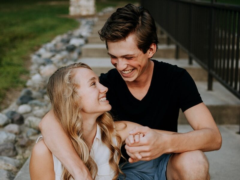 man holding the hand of a woman while siting on concrete staircase