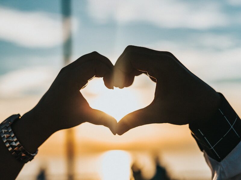 person forming heart with their hands