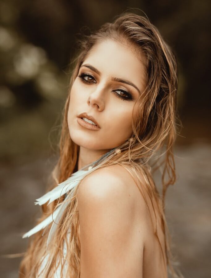 focus photography of blonde woman with feather earring