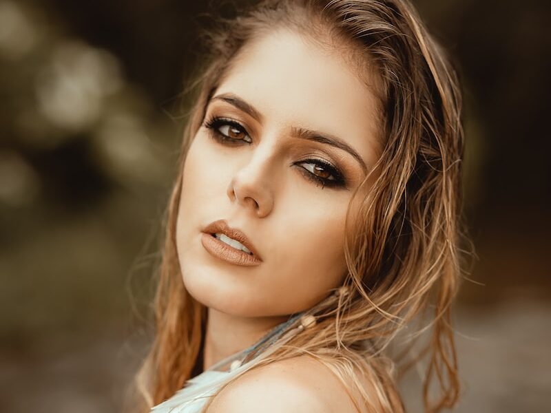 focus photography of blonde woman with feather earring